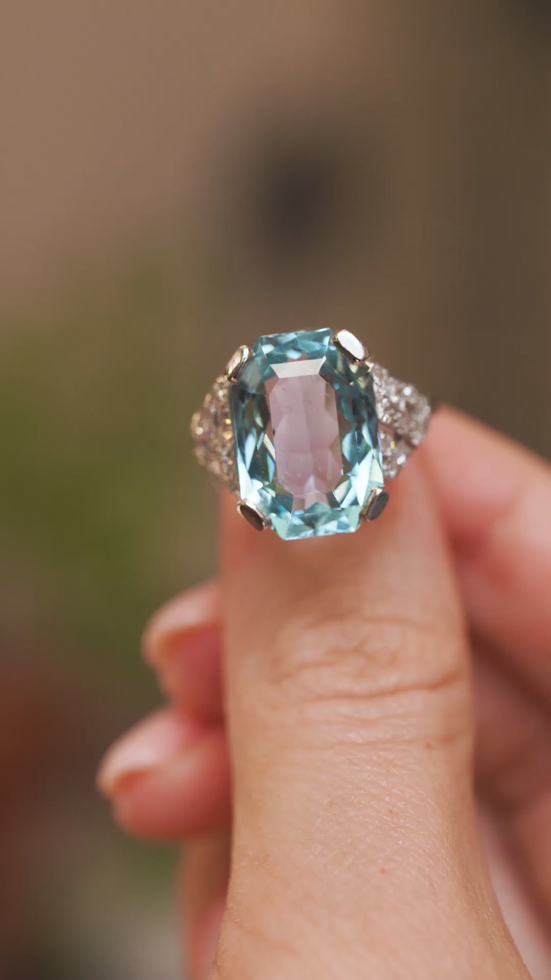 Video close-up of an antique octagonal aquamarine ring balanced on a fingertip, displaying its diamond-set platinum mount.