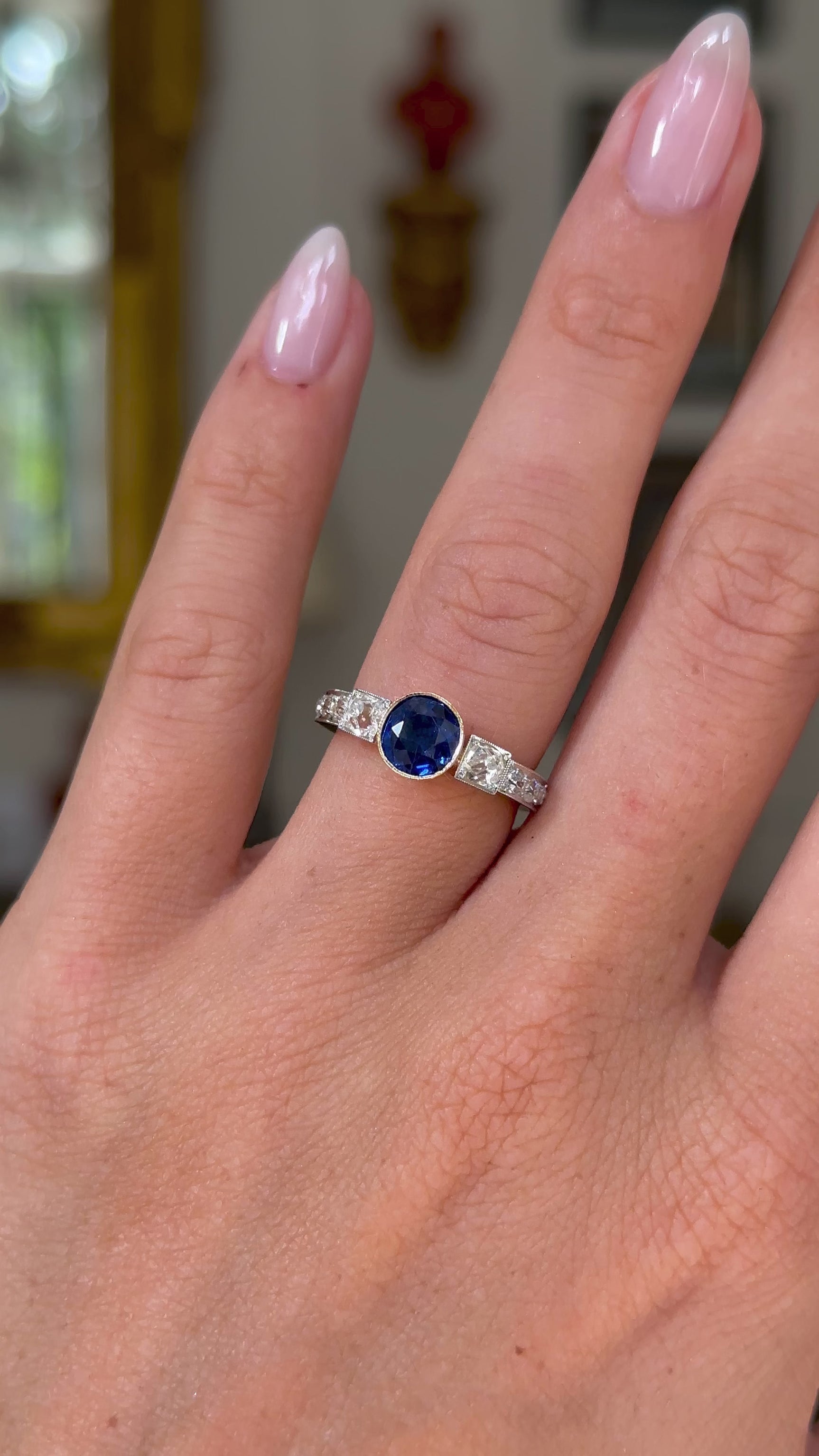 Art Deco sapphire and diamond engagement ring, worn on hand and moved away from lens to give perspective,front view. 