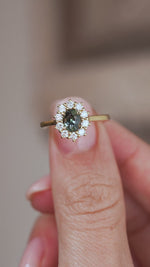 Video close-up of the antique-inspired cluster ring balanced on a fingertip, displaying the oval sapphire and individual diamond settings.