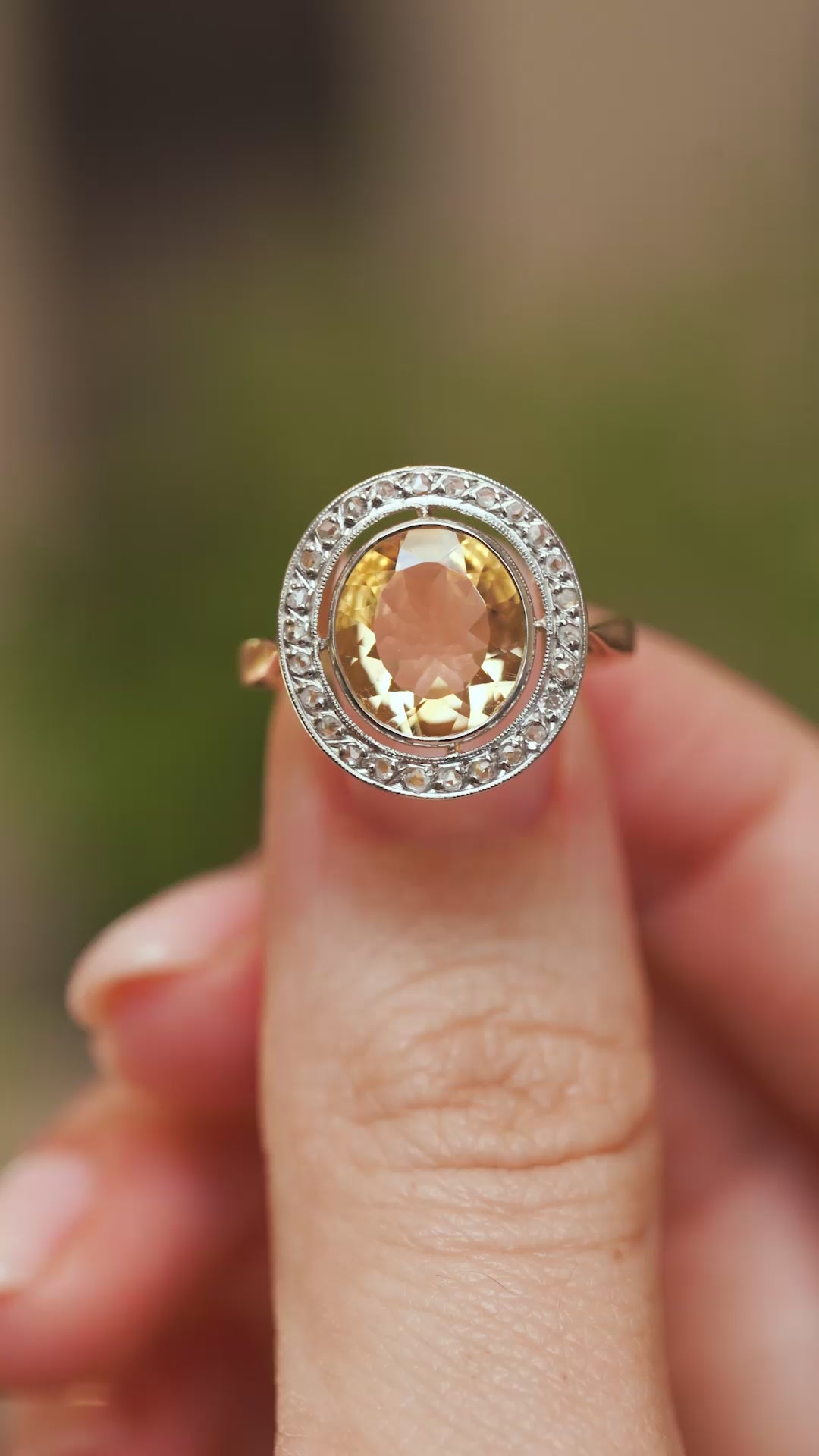 Video close-up of a French Belle Époque citrine and diamond ring balanced on a fingertip, highlighting its ornate antique cluster design.