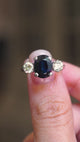 A vintage, 1970's midnight-blue sapphire and diamond three-stone ring in white gold shown in video between fingers.