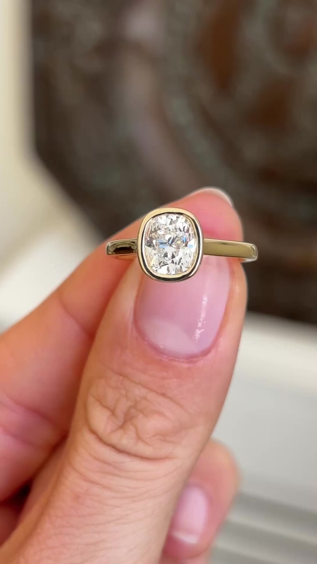 Antique-inspired cushion old-cut diamond solitaire engagement ring showcasing a cushion-shaped old-cut diamond and elegant solitaire setting, held by hand.