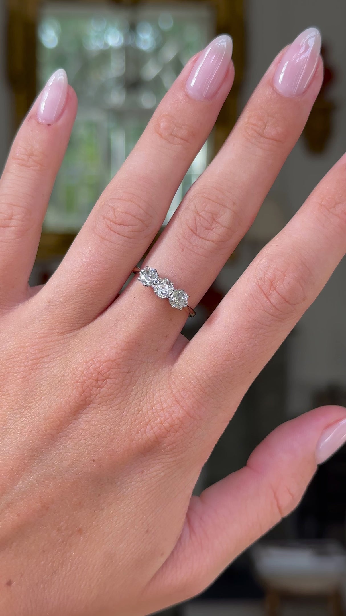 antique three stone diamond engagement ring, 18ct yellow gold band, worn on hand and moved away from lens to give perspective, front view. 