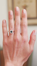 Teal sapphire cluster ring worn on hand showing blue green colour shift in movement.