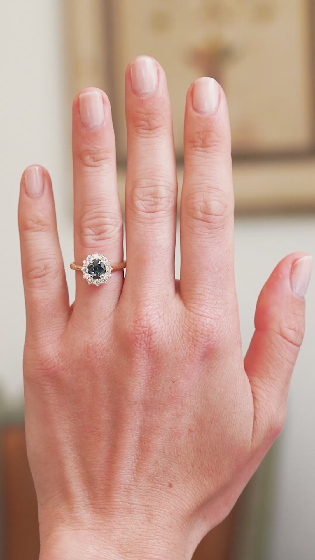 Teal sapphire cluster ring worn on hand showing blue green colour shift in movement.