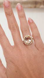 Video showcasing the oval-cut topaz and diamond halo ring on the hand as the gemstones catch the light.