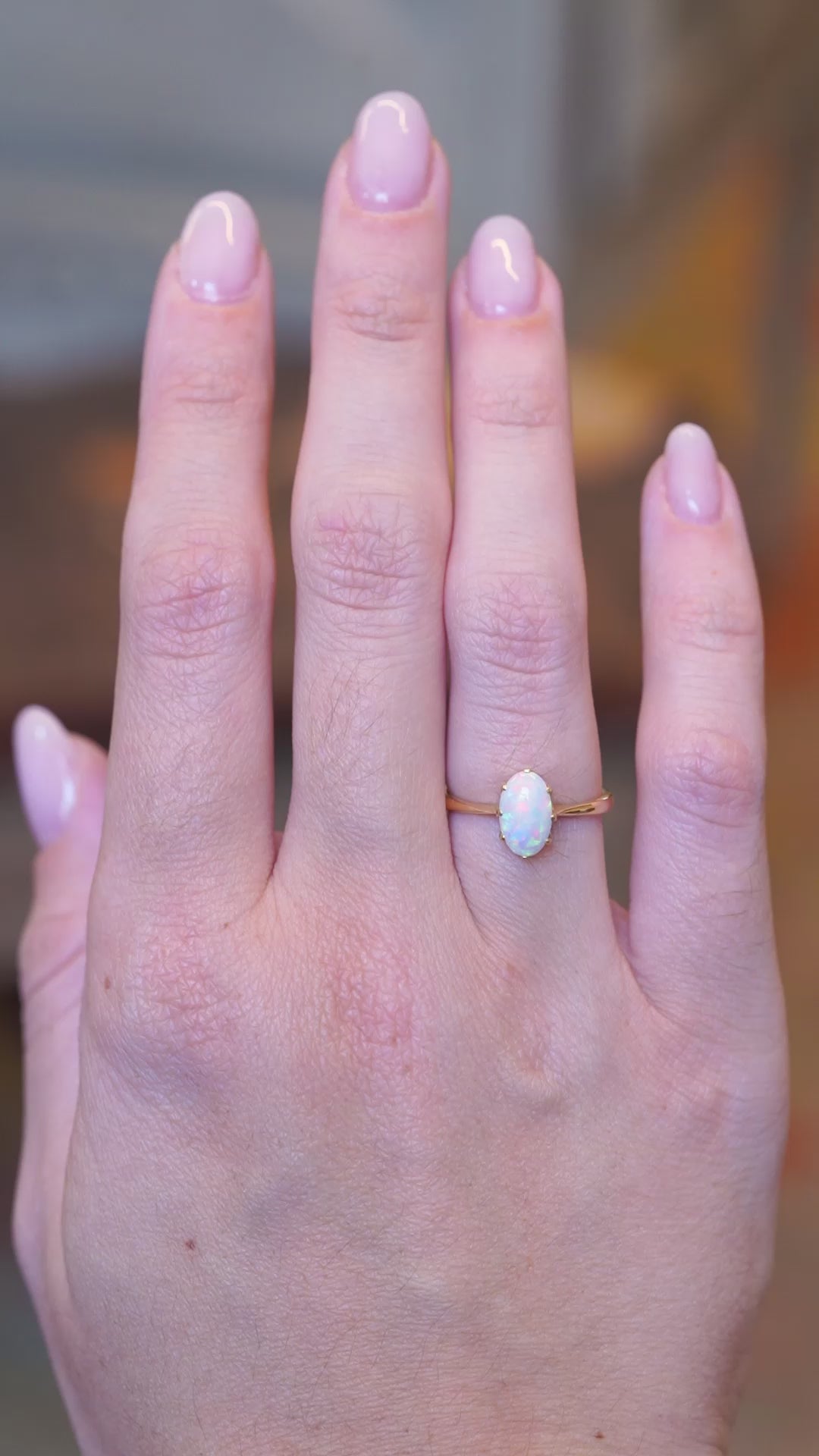 Vintage 1990s precious opal solitaire ring worn on hand in motion.