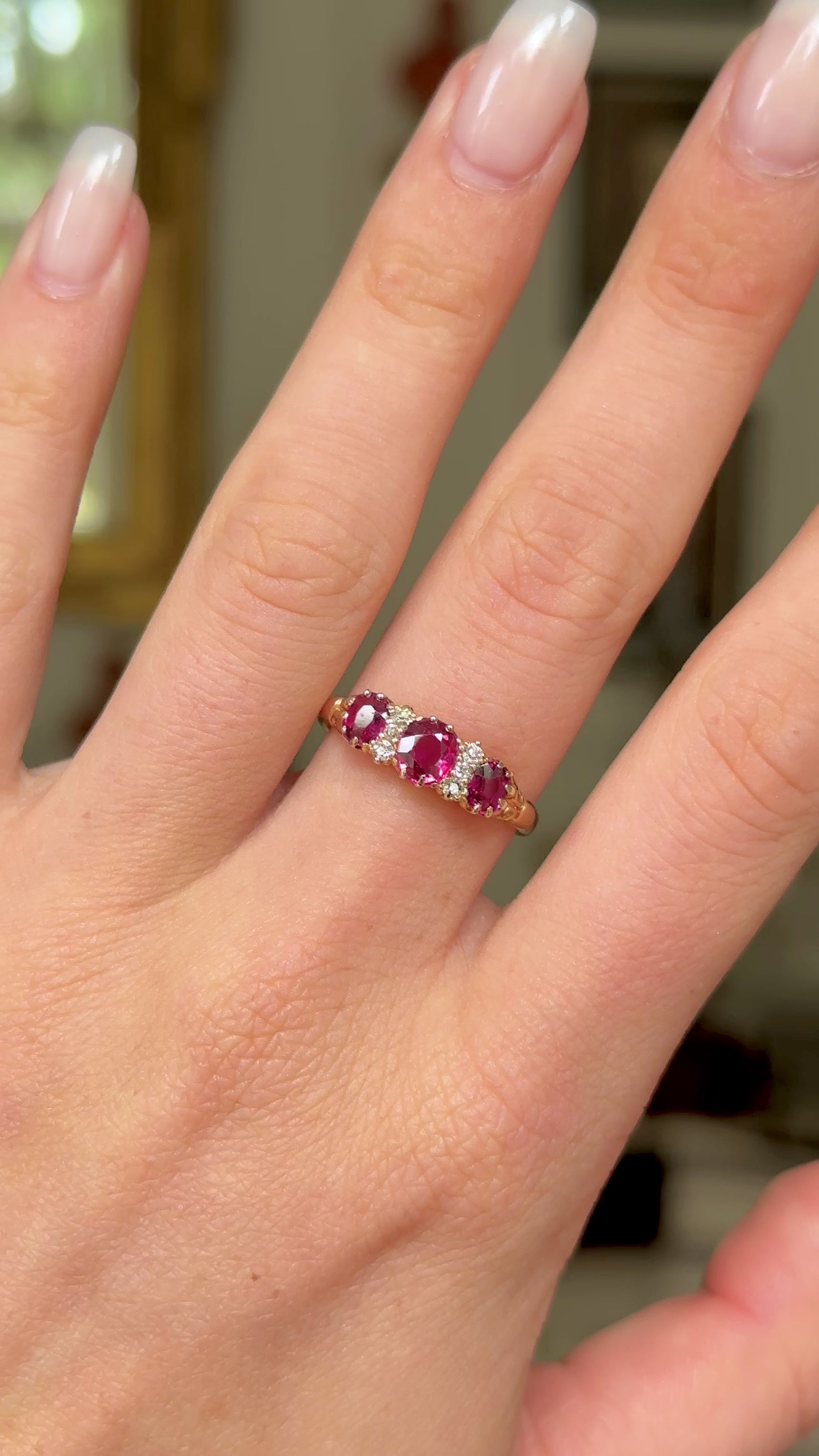 Victorian three-stone ruby and diamond engagement ring, worn on hand and rotated to give perspective.