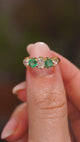 A video of an Antique, Victorian emerald and diamond five-stone engagement ring in yellow gold held in between the fingers and slowly rotated to show off various different angles.