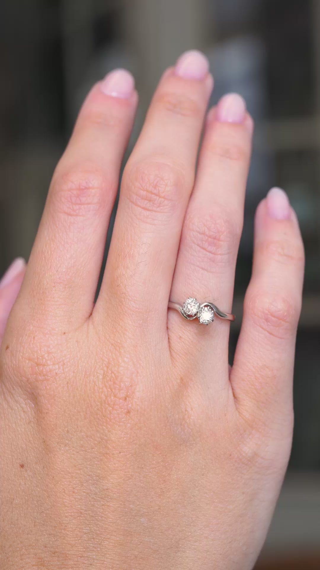A video of an Antique, Edwardian toi et moi diamond engagement ring with two diamonds set and mounted in platinum worn on an outstretched hand as it slowly moves.