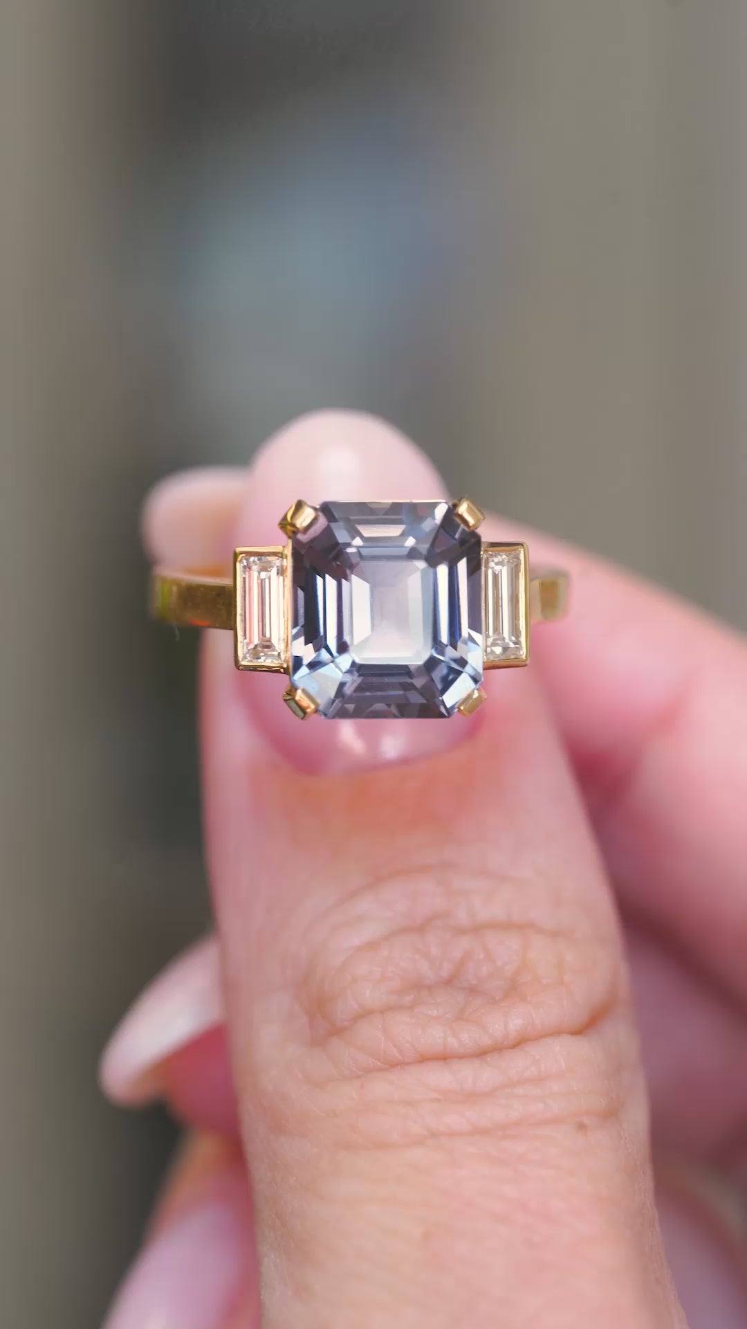 A video of a close-up of an emerald-cut blue spinel flanked by baguette diamonds.