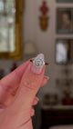 antique diamond cluster engagement ring, held in fingers and rotated to give perspective, front view.