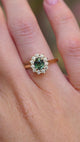 A video of an antique-inspired teal sapphire and diamond halo engagement ring in 14ct yellow gold worn on the hand.