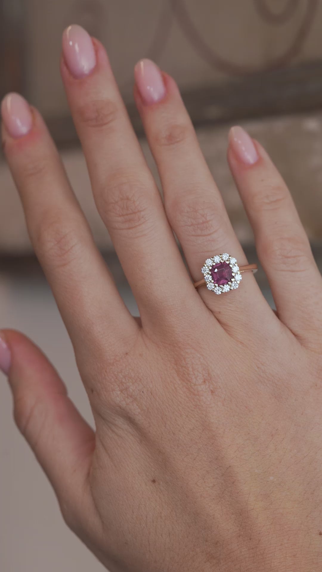 A video of the pink sapphire cluster ring worn on a finger, capturing the gemstone's rosy tones and sparkling diamond halo.