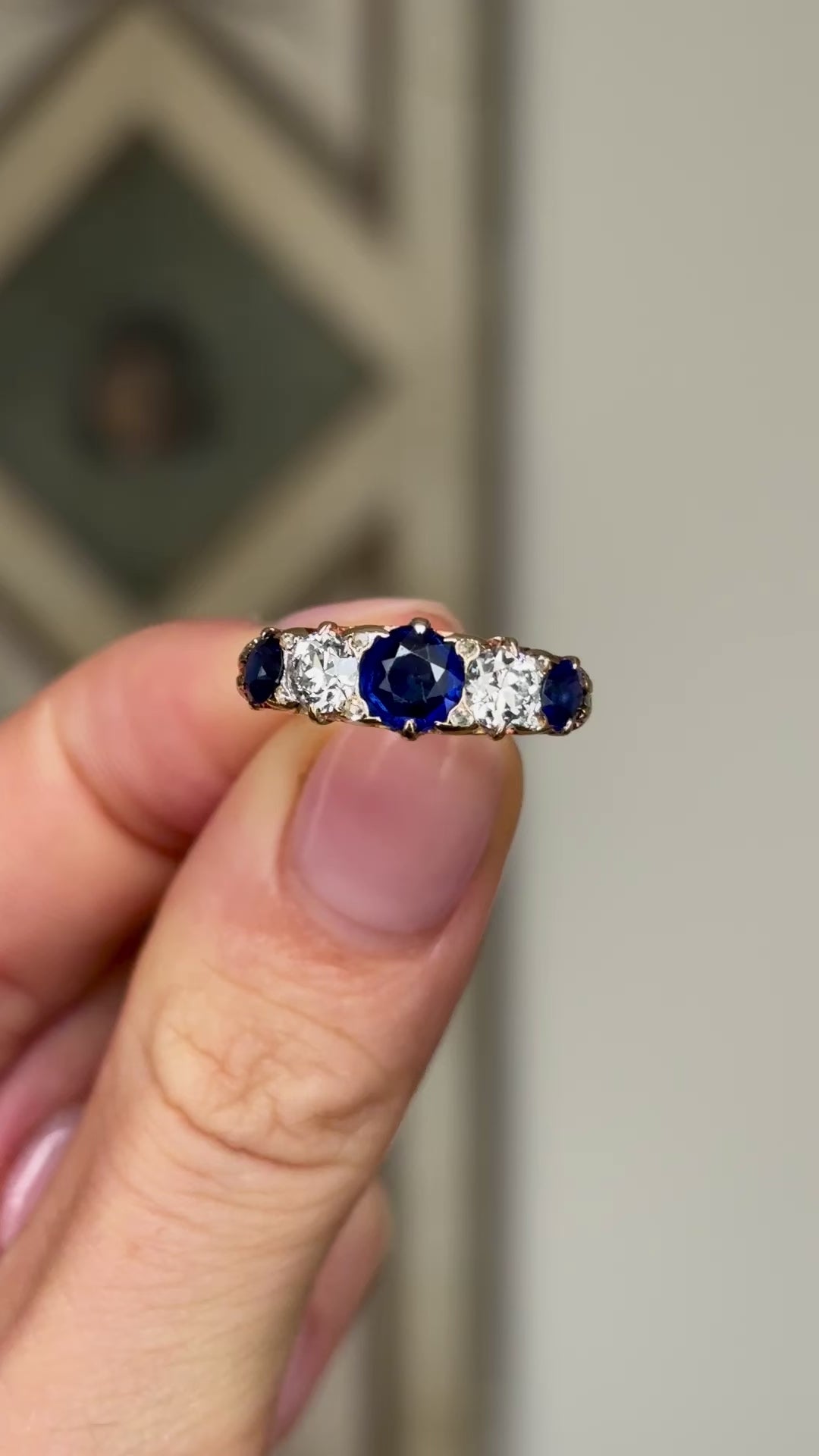 Antique, Victorian sapphire and diamond five-stone ring held in fingers.