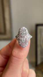 Close-up video of an antique 1920s platinum cocktail ring featuring an elaborate filigree setting and brilliant diamond cluster, highlighting exceptional craftsmanship, sparkle and Art Deco design.