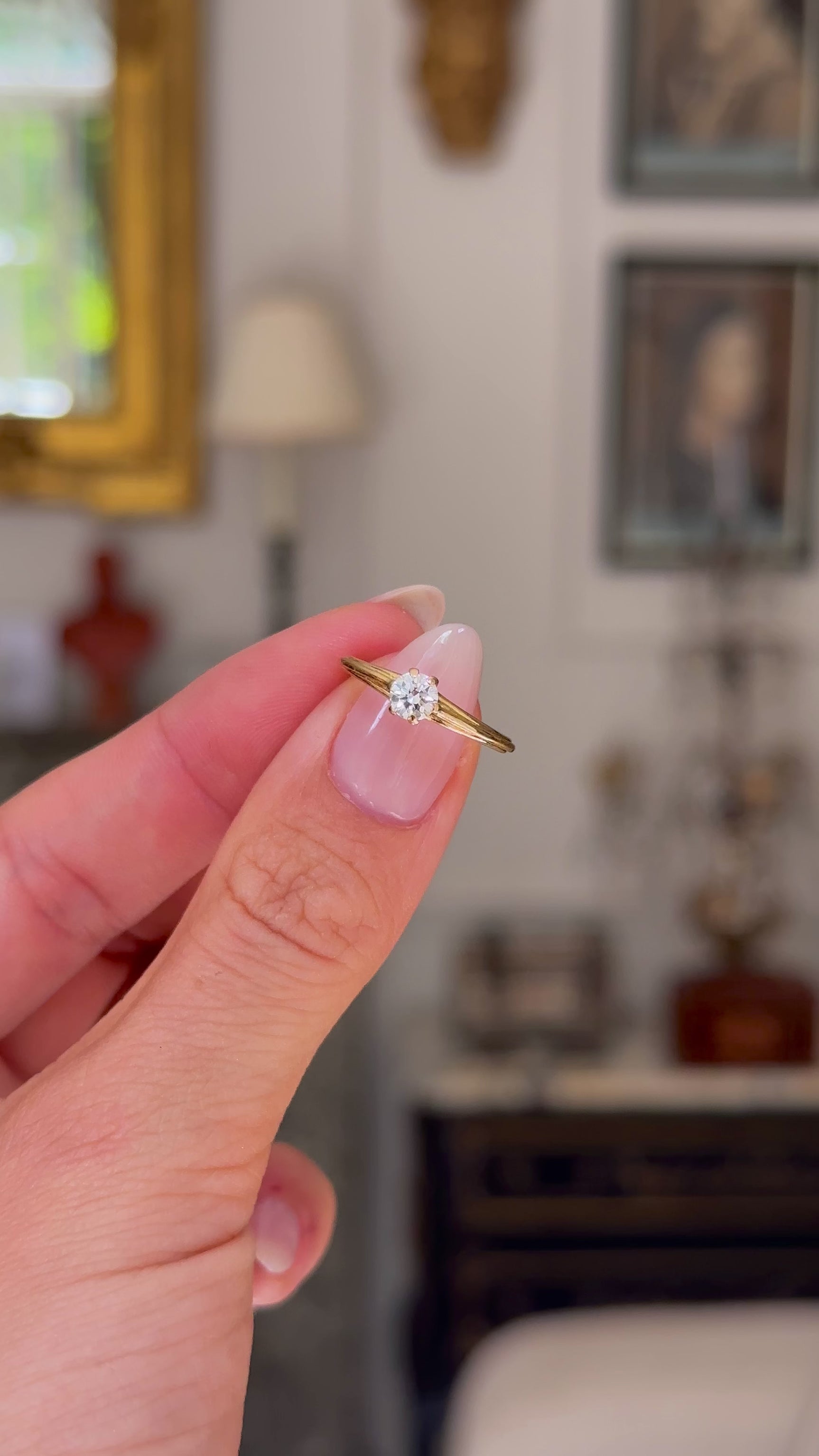 Vintage solitaire diamond engagement ring held in fingers and moved around to give perspective.