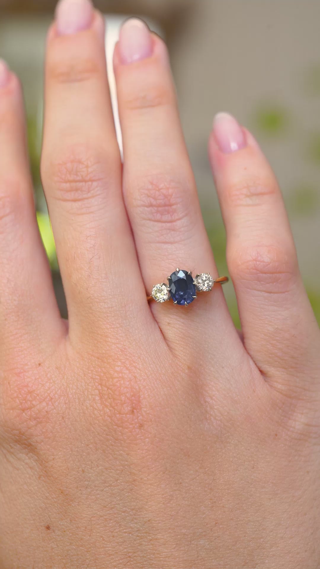 A video of an Antique, Art Deco sapphire and diamond trilogy engagement ring mounted on a yellow gold band and worn on the hand as its moved.