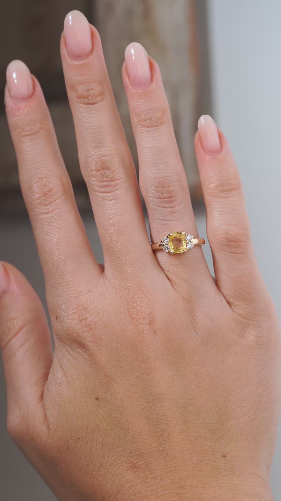 A video of the yellow sapphire and diamond cluster engagement ring worn on a hand, capturing the gemstone's golden reflections, surrounding diamonds and elegant yellow gold setting.