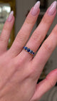 sapphire and diamond five stone ring worn on hand and moved away from lens to give perspective.