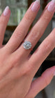 antique diamond cluster engagement ring, worn on hand and moved away from lens to give perspective, front view.