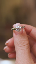 Video close-up of a vintage brilliant-cut lab diamond ring balanced on a fingertip, highlighting its sparkle and claw setting.