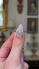  edwardian diamond daisy cluster engagement ring, held in fingers and rotated to give perspective,front view. 