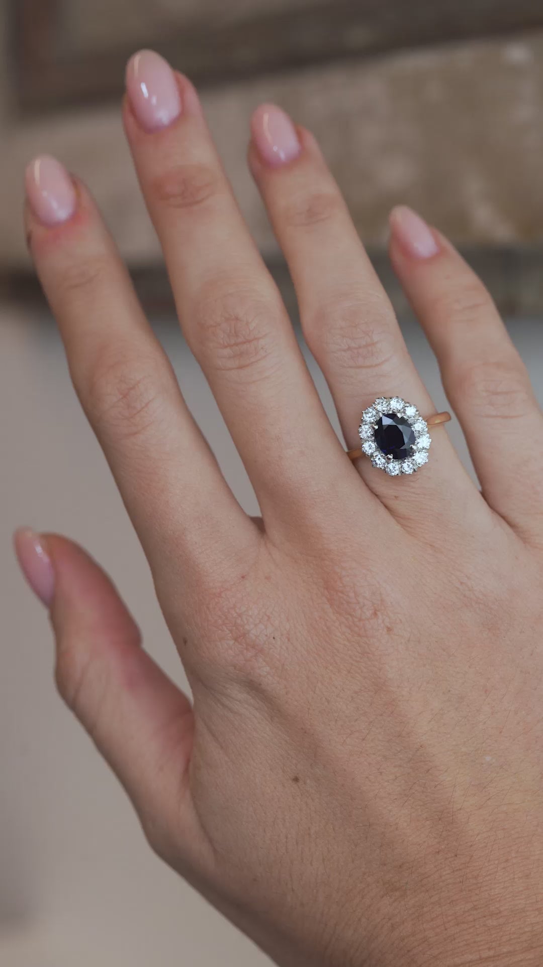 A video of the sapphire cluster ring worn on a finger, capturing the deep blue gemstone and sparkling diamond surround.
