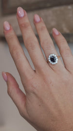 A video of the sapphire cluster ring worn on a finger, capturing the deep blue gemstone and sparkling diamond surround.