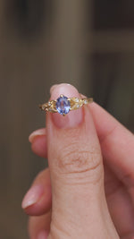 Video presenting the vintage-inspired sapphire engagement ring balanced on a fingertip for a clear view of its ornate shoulders.