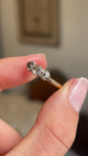 Detailed video of an antique Edwardian three-stone ring in yellow gold, held between fingers to showcase old-cut brown, pink and champagne coloured diamonds, their subtle natural tones and elegant early 20th-century design against a warm interior setting.