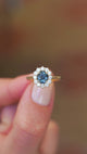 Sapphire and diamond cluster ring showing central teal stone with surrounding sparkle.