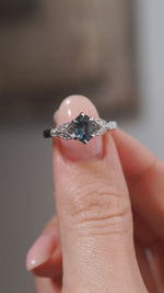 A close-up video of the sapphire and diamond ring held between fingers, highlighting the gemstone's darker blue reflections and intricate diamond-set detailing.