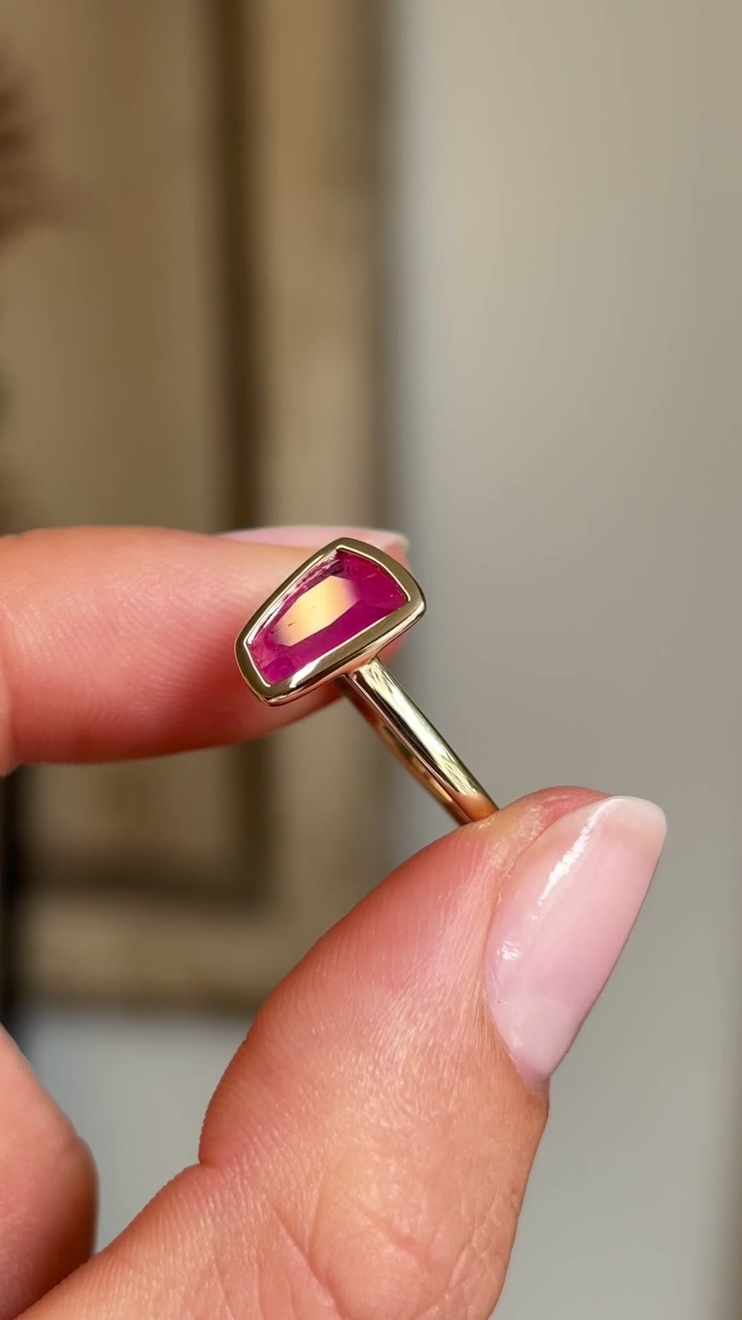 Video of a Vintage-inspired, pink ruby solitaire engagement ring in yellow gold held between two fingers and rotated to see all the angles