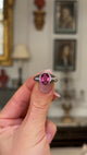 vintage pink sapphire, diamond and platinum ring held in fingers and moved around to give perspective.