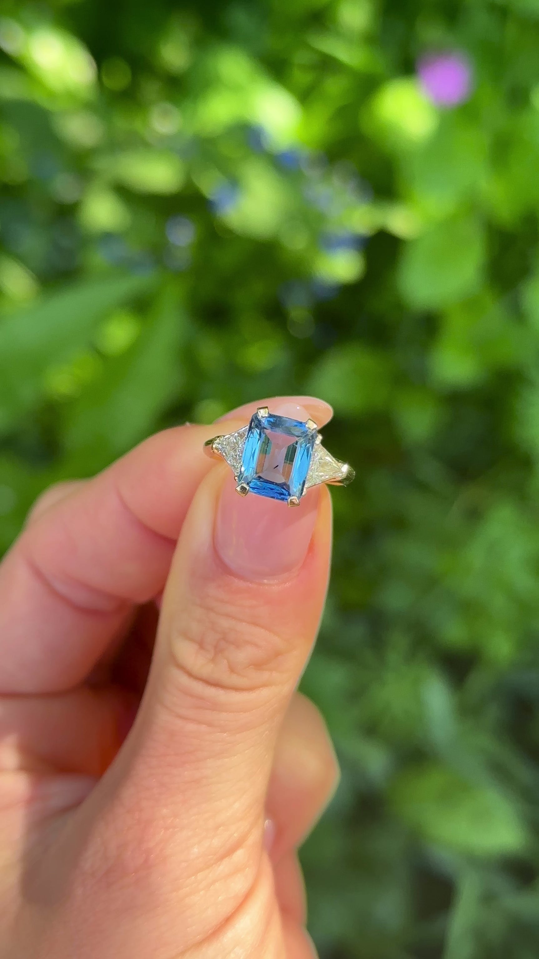 Vintage, Blue Sapphire and Trilliant-cut Diamond Three Stone ring, 18ct Yellow Gold held in fingers.