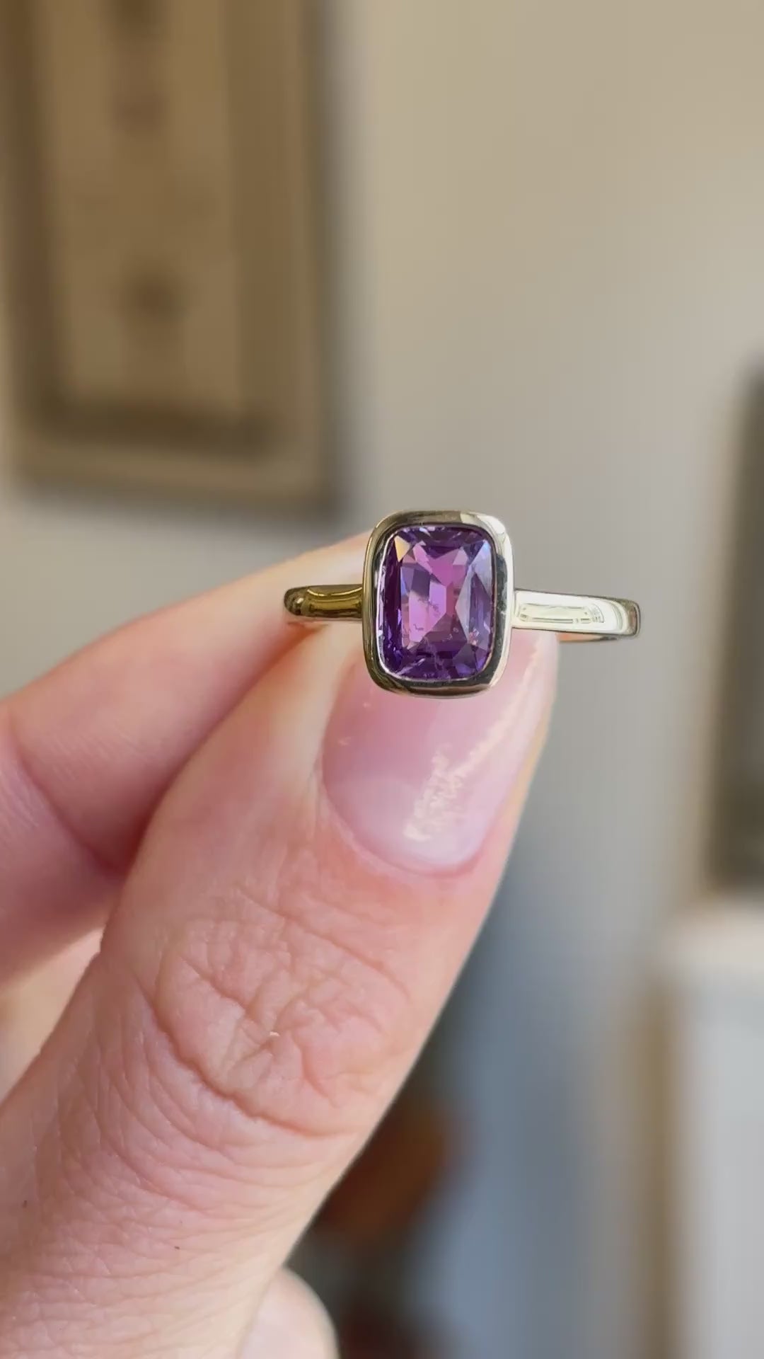 Royal purple cushion-cut sapphire solitaire engagement ring showcasing a cushion-cut purple sapphire centre stone, held by hand to highlight the setting and craftsmanship.