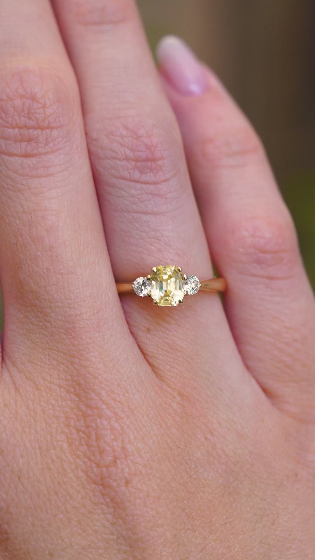 A video of a vintage-inspired yellow sapphire and diamond three-stone ring in yellow gold worn on a hand.