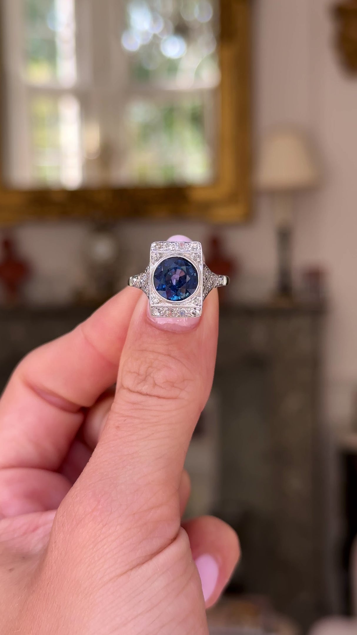 sapphire and diamond panel ring held in fingers and moved around to give perspective.