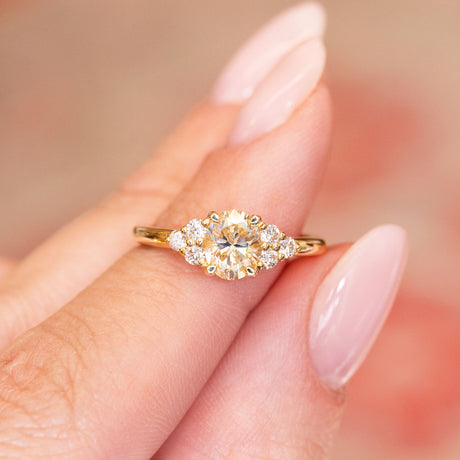 Antique-inspired primrose yellow diamond cluster tre-foil engagement ring with oval yellow diamond and surrounding diamond clusters.