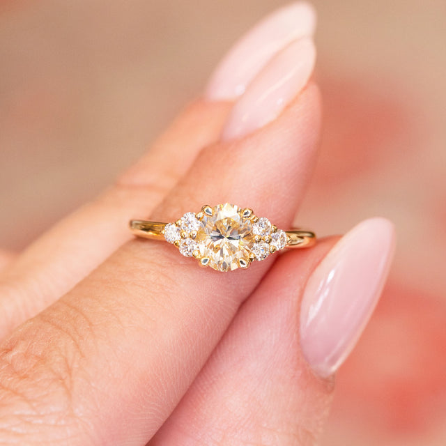 Antique-inspired primrose yellow diamond cluster tre-foil engagement ring with oval yellow diamond and surrounding diamond clusters.