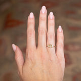 Antique-inspired primrose yellow diamond cluster tre-foil engagement ring worn on hand with gold band.