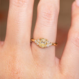 Antique-inspired primrose yellow diamond cluster tre-foil engagement ring with oval yellow diamond centre stone worn on finger.