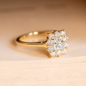 Antique inspired princess-cut diamond cluster engagement ring showcasing a central princess-cut diamond within a brilliant-cut diamond cluster setting.