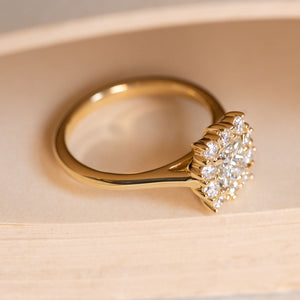 Antique inspired princess-cut diamond cluster engagement ring displaying the raised cluster setting and yellow gold band.