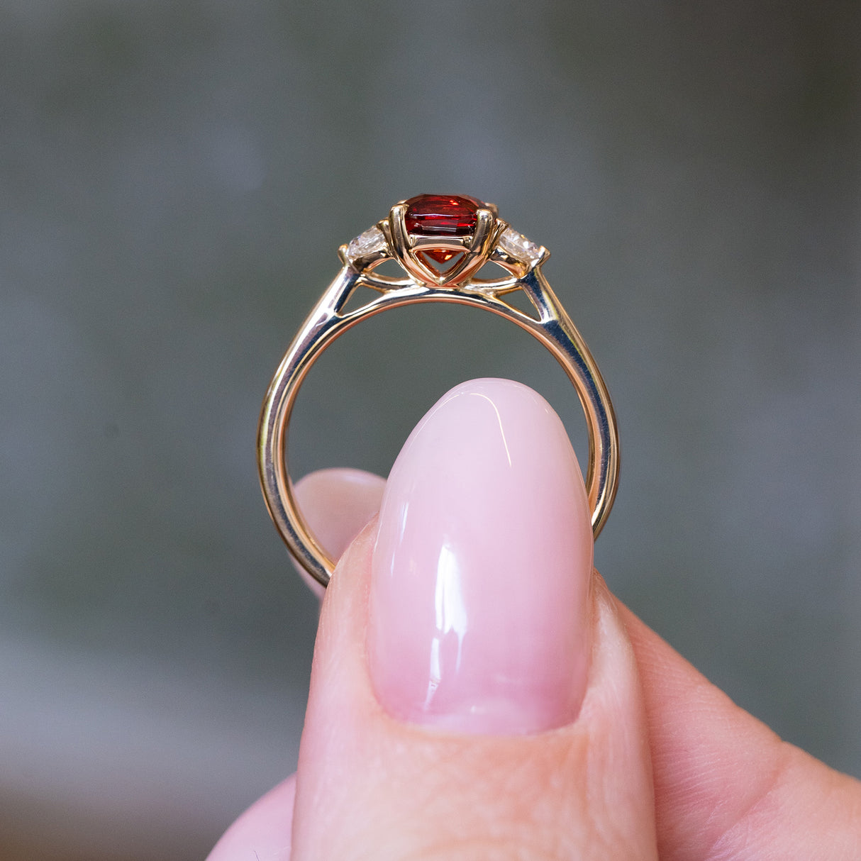 Red spinel and diamond three-stone engagement ring showing raised gold setting and under gallery.