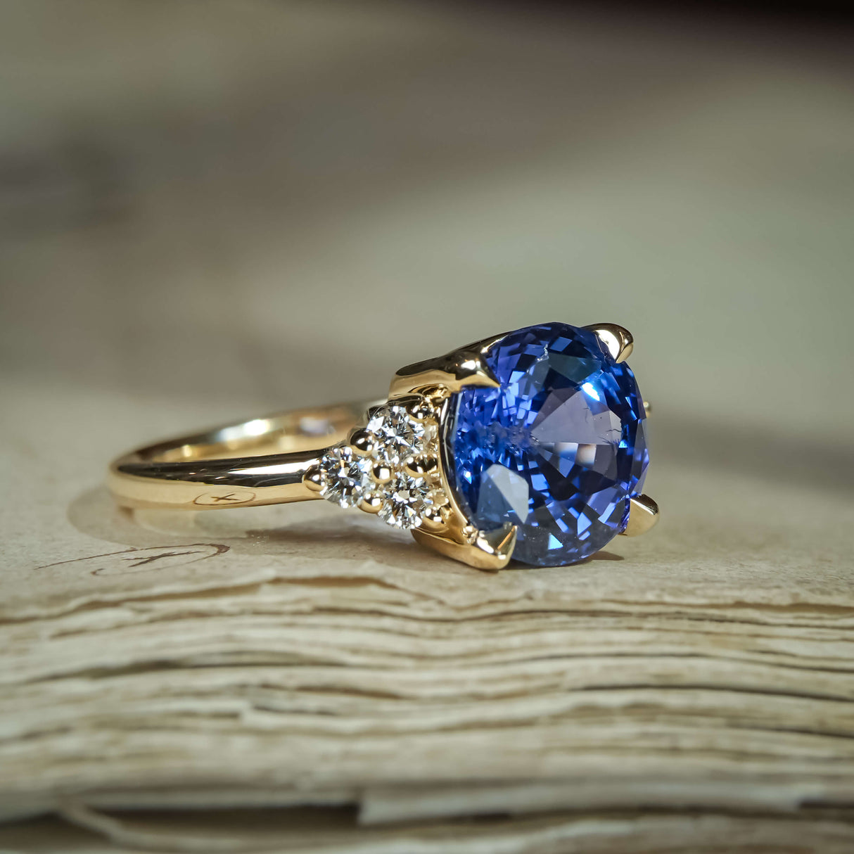 Round blue sapphire ring with diamond trefoil side stones in yellow gold setting