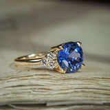 Round blue sapphire ring with diamond trefoil side stones in yellow gold setting
