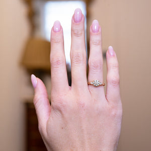 Round brilliant-cut diamond three-stone engagement ring worn on hand with tapered diamond side stones.