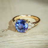 Round-cut blue sapphire ring with diamond trefoil side stones on gold band